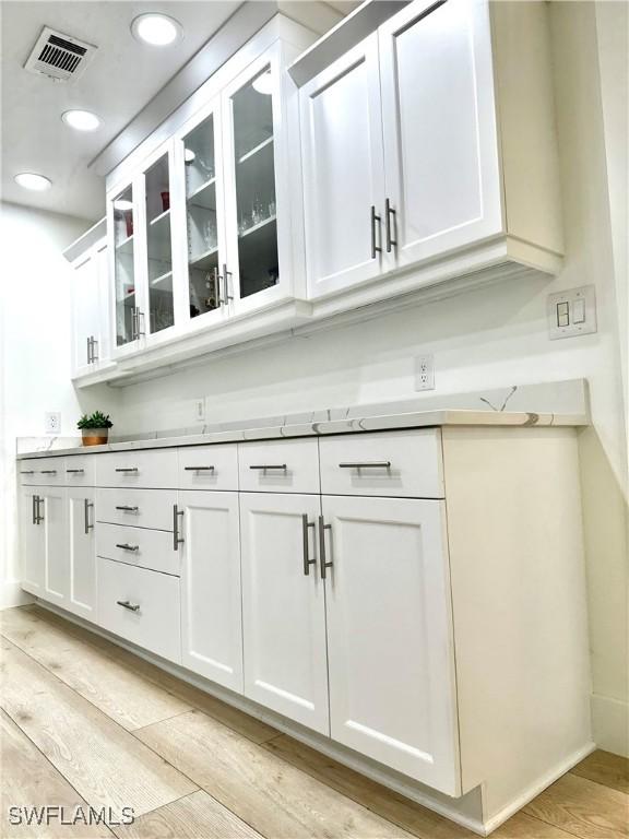 bar featuring white cabinetry and light hardwood / wood-style flooring