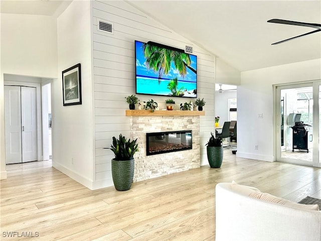 living room featuring light hardwood / wood-style flooring, high vaulted ceiling, ceiling fan, and wood walls