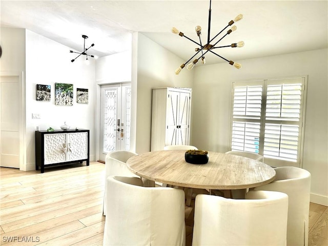 dining space featuring an inviting chandelier, vaulted ceiling, and light hardwood / wood-style floors