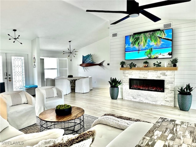 living room with ceiling fan with notable chandelier, wood-type flooring, wooden walls, and vaulted ceiling