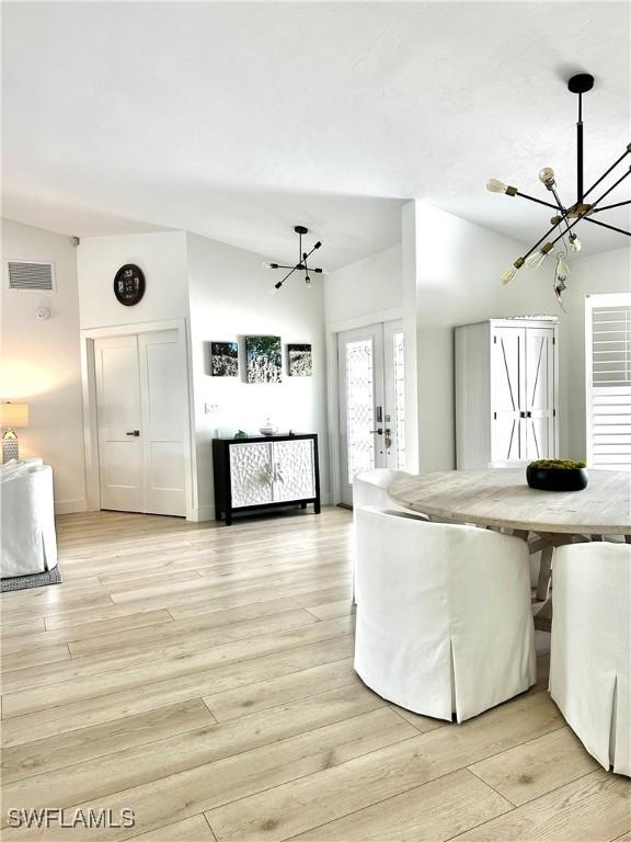 9553 Campbell Cir, Naples, FL 34109 - unfurnished living room with french doors, a notable chandelier, light wood finished floors, and visible vents