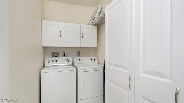 clothes washing area featuring independent washer and dryer and cabinets