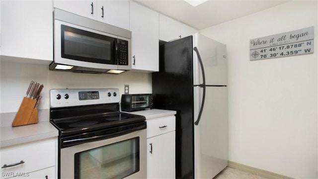 kitchen featuring appliances with stainless steel finishes, light tile patterned floors, and white cabinets