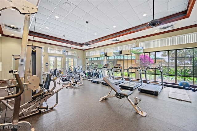 workout area with a paneled ceiling, a high ceiling, ornamental molding, and a tray ceiling