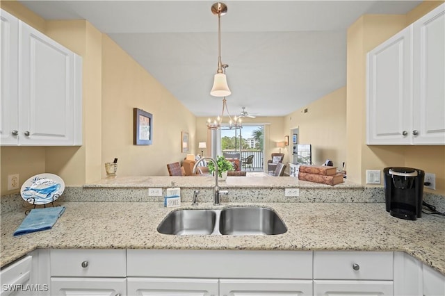 kitchen featuring a sink, a chandelier, open floor plan, and white cabinetry