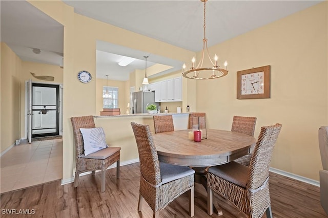 dining space with a chandelier, baseboards, and wood finished floors