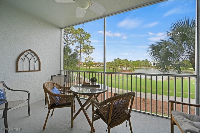 sunroom / solarium with ceiling fan and a water view