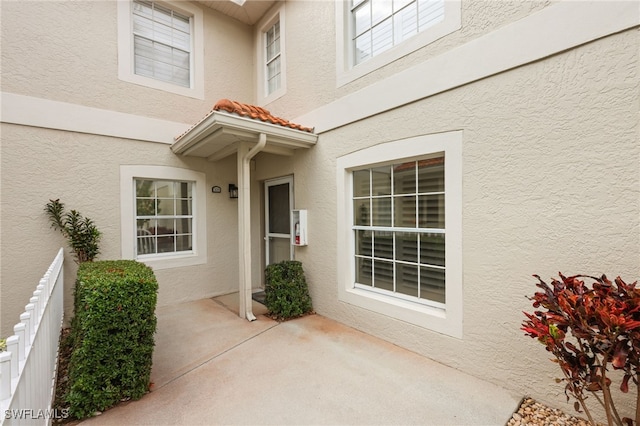 entrance to property with a tiled roof and stucco siding