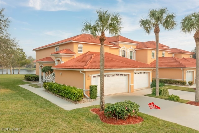 mediterranean / spanish house with a front lawn, a garage, and a water view