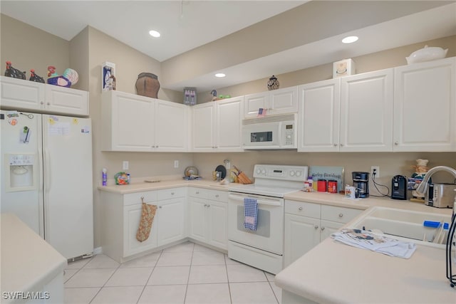 kitchen with white appliances, sink, light tile patterned floors, and white cabinetry