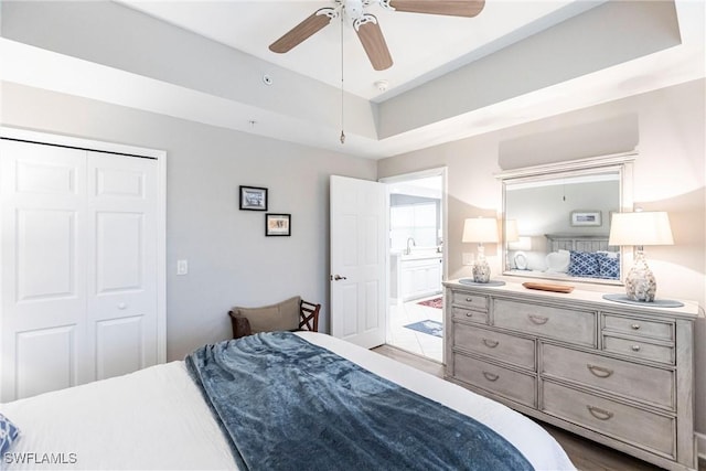 bedroom featuring ceiling fan, a raised ceiling, and a closet