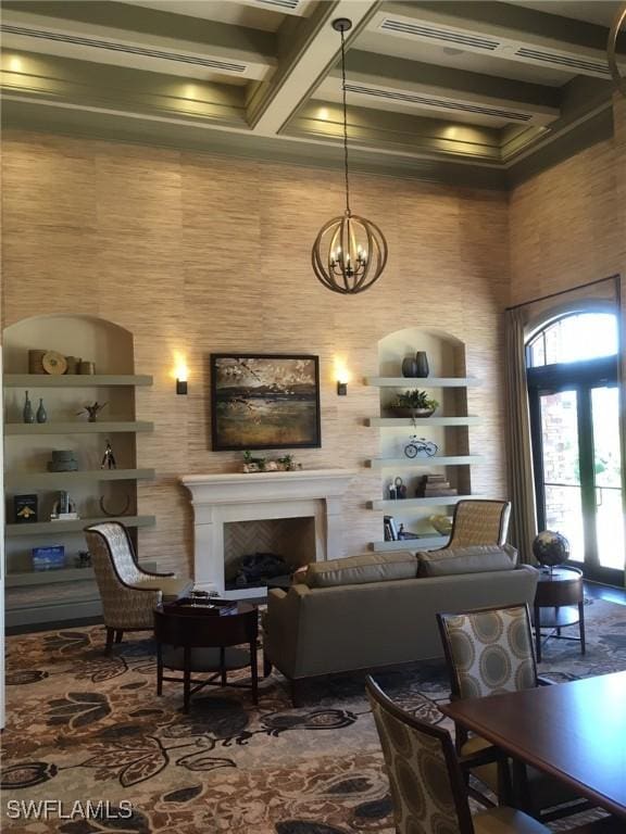 living room featuring a notable chandelier, beam ceiling, coffered ceiling, built in features, and french doors