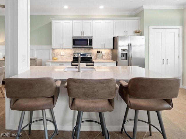 kitchen featuring sink, white cabinets, appliances with stainless steel finishes, and a breakfast bar