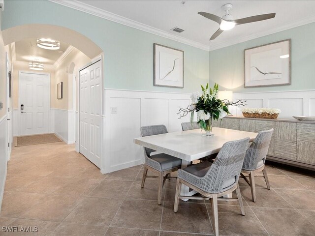 tiled dining room featuring ceiling fan and crown molding