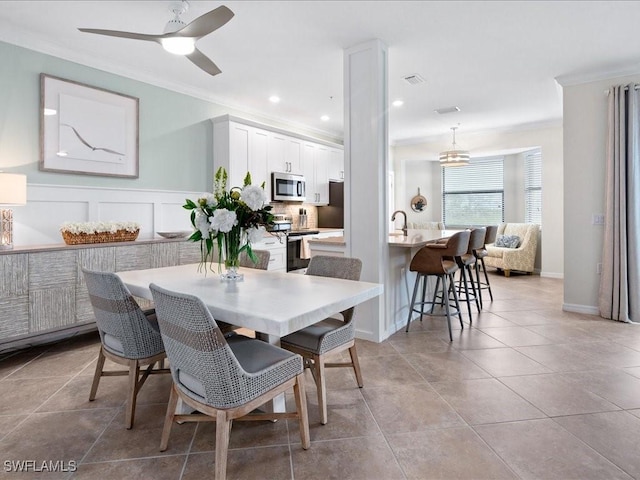 dining space with ceiling fan, light tile patterned floors, sink, and ornamental molding