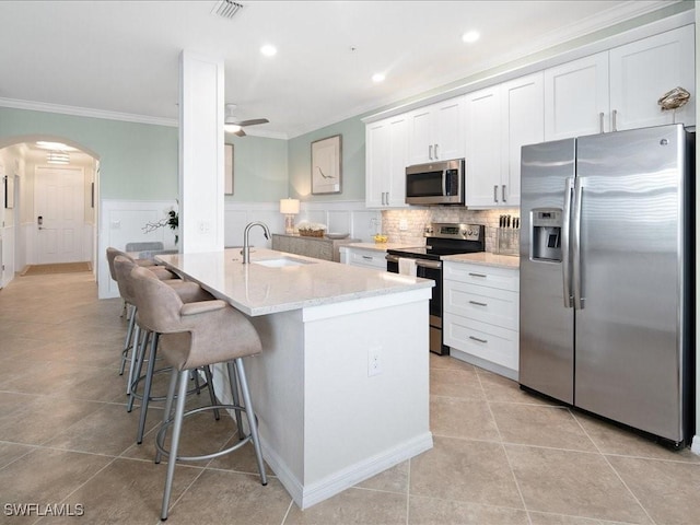 kitchen featuring ceiling fan, sink, white cabinetry, appliances with stainless steel finishes, and ornamental molding