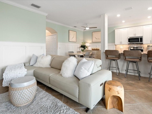 living room featuring ceiling fan, tile patterned flooring, and crown molding