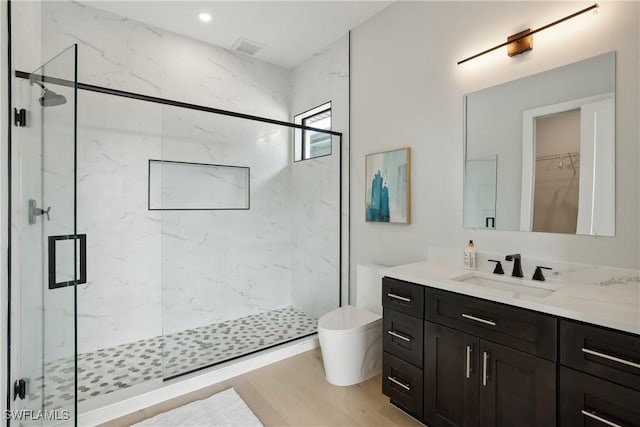 bathroom featuring walk in shower, vanity, wood-type flooring, and toilet