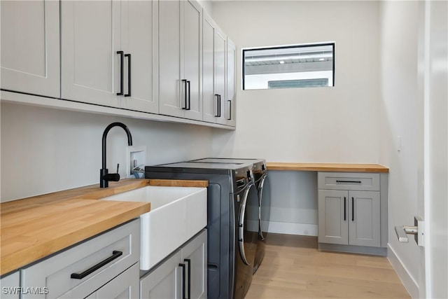 laundry area with light hardwood / wood-style floors, cabinets, and separate washer and dryer