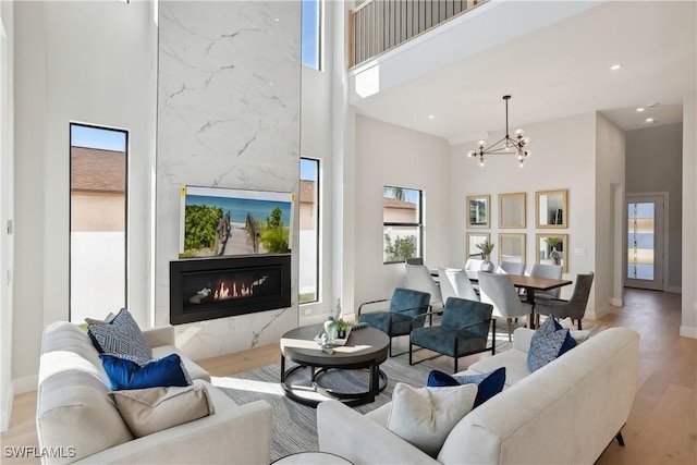 living room with light hardwood / wood-style floors, a chandelier, a towering ceiling, and a fireplace