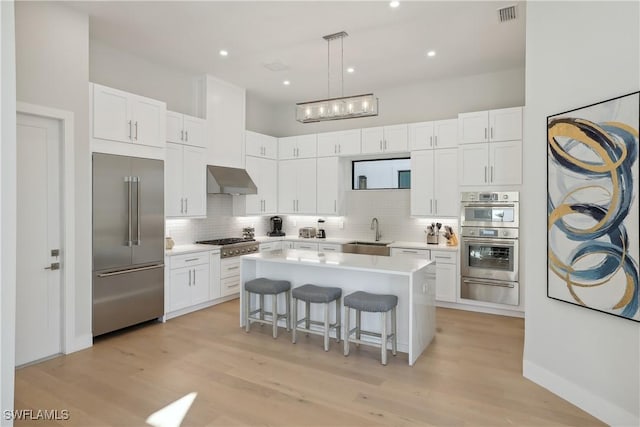 kitchen with decorative light fixtures, a breakfast bar, white cabinets, and appliances with stainless steel finishes