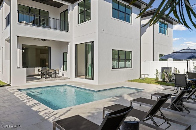 rear view of property featuring a fenced in pool, a patio area, and a balcony