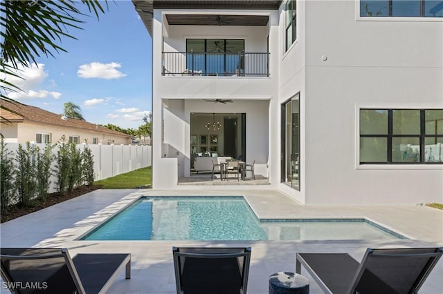 rear view of property with a balcony, a patio area, a fenced in pool, and ceiling fan