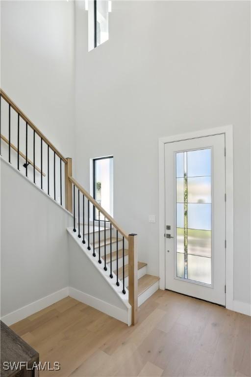 entryway featuring a wealth of natural light, a towering ceiling, and hardwood / wood-style floors