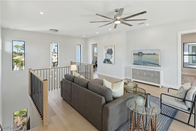 living room featuring ceiling fan, radiator, a wealth of natural light, and light hardwood / wood-style flooring