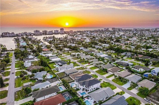 aerial view at dusk featuring a water view