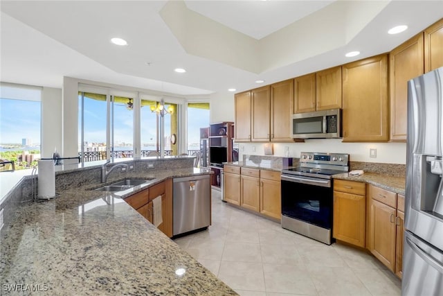 kitchen with light stone counters, appliances with stainless steel finishes, sink, and pendant lighting