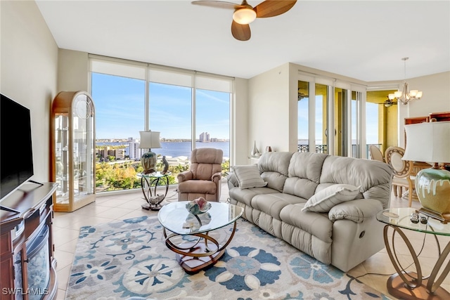 tiled living room featuring floor to ceiling windows, a water view, and ceiling fan with notable chandelier