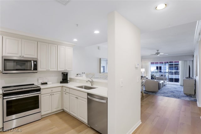 kitchen featuring stainless steel appliances, sink, white cabinetry, ceiling fan, and light wood-type flooring