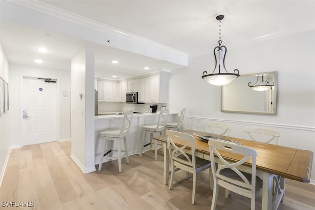 dining space with ornamental molding and light hardwood / wood-style floors