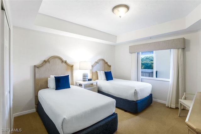 bedroom with light colored carpet and a tray ceiling