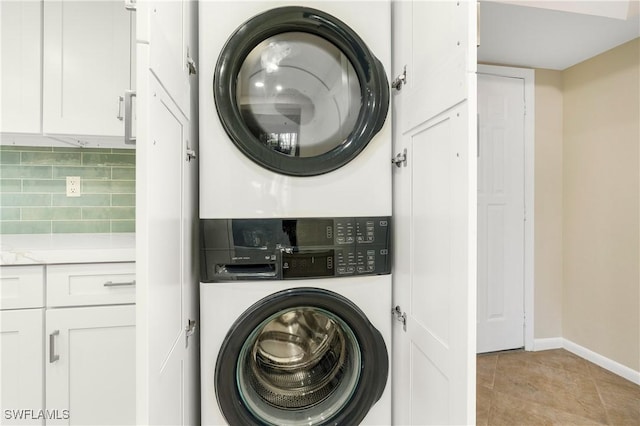 laundry area with light tile patterned floors and stacked washer and clothes dryer