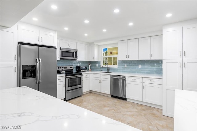 kitchen with white cabinets, light stone countertops, sink, and stainless steel appliances