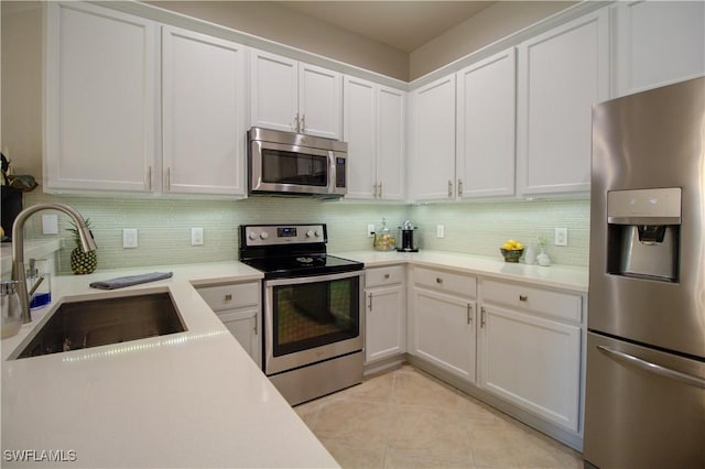 kitchen with white cabinets, appliances with stainless steel finishes, sink, and light tile patterned flooring