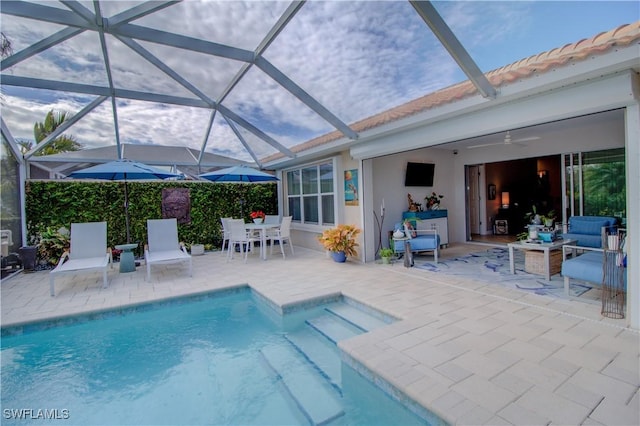 view of swimming pool featuring ceiling fan, glass enclosure, and a patio