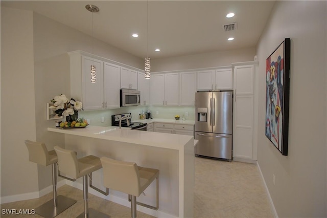 kitchen with kitchen peninsula, stainless steel appliances, pendant lighting, and white cabinets