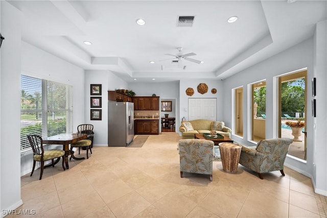 tiled living room featuring a tray ceiling and ceiling fan