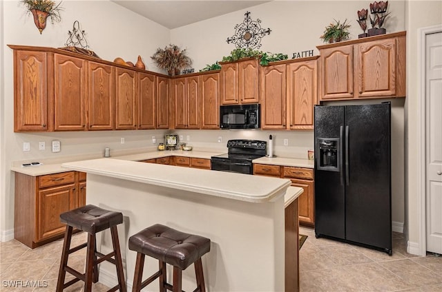 kitchen featuring light tile patterned floors, a breakfast bar area, and black appliances