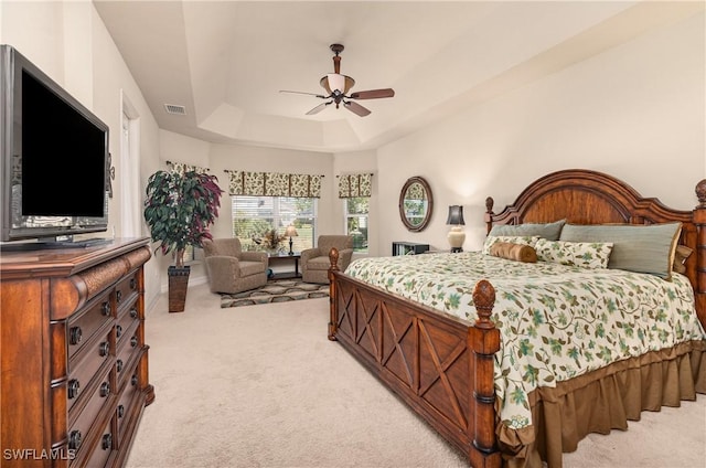 carpeted bedroom featuring ceiling fan and a tray ceiling