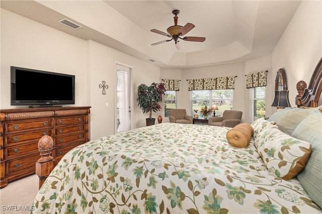 bedroom featuring a raised ceiling, light colored carpet, and ceiling fan