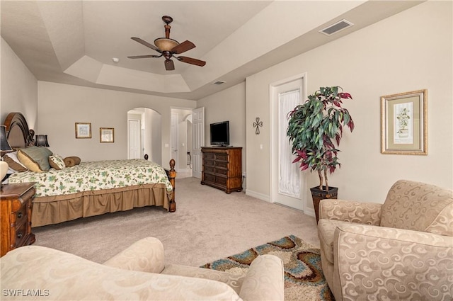 carpeted bedroom featuring ceiling fan and a tray ceiling