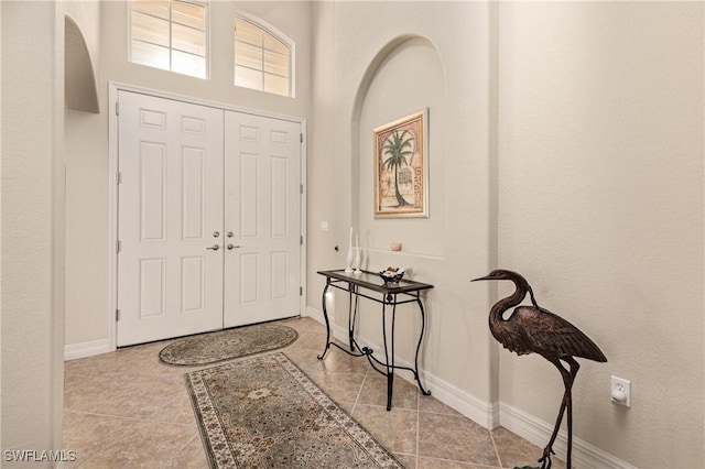 tiled foyer entrance featuring a towering ceiling