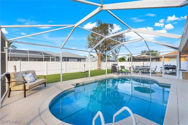 view of swimming pool featuring a lawn, a patio area, and glass enclosure