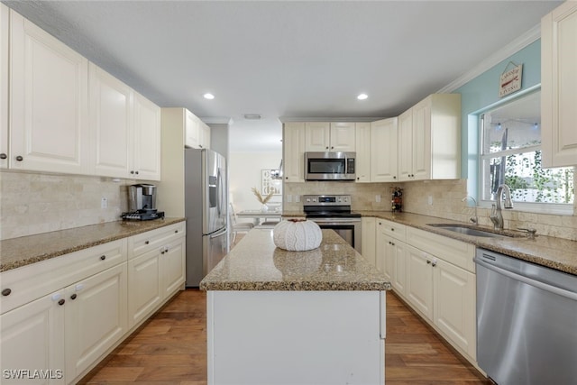 kitchen featuring a kitchen island, light stone countertops, appliances with stainless steel finishes, and sink