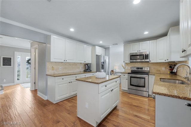 kitchen with a kitchen island, white cabinets, appliances with stainless steel finishes, and sink