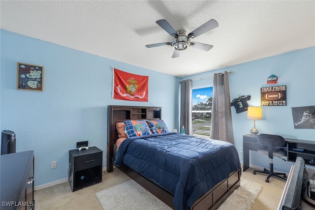 bedroom with ceiling fan, light colored carpet, and a textured ceiling